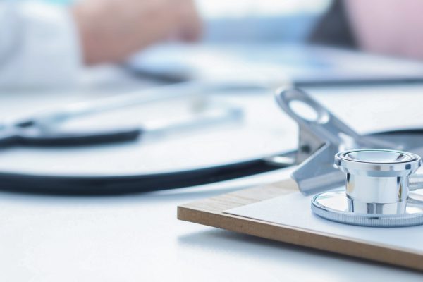 Stethoscope and clip board on the doctor workplace close up